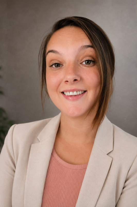 Meet our team: A woman with brown hair in a beige blazer and pink top smiles at the camera against a neutral background.